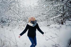 blond flicka ha kul med snö på vinterdagen. foto