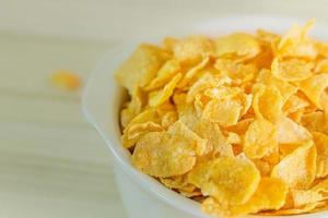 bild närbild cornflakes spannmål frukost i vit skål på träbord. foto