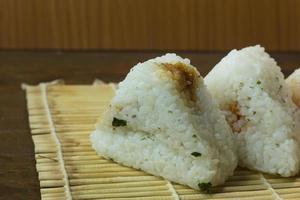 den japanska maten onigiri vitt ris formas till triangulära eller cylindriska former och ofta insvept i nori. foto