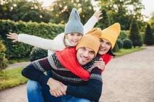 ha trevlig tid tillsammans leende upprymd kvinna, man och deras lilla kvinnliga barn, bär varma stickade kläder, omfamna varandra, gå i parken, vara på gott humör. familj ger stöd, uppmuntran foto