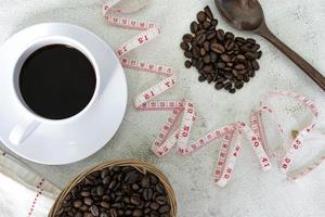 kopp kaffe och kaffebönor bakgrund med mått kran på vitt skrivbord. foto