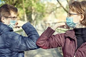 två personer stöter på armbågarna för att undvika coronavirus utomhus. vänner visar ett nytt sätt att hälsa under coronavirusepidemin. hälso-och sjukvård koncept. social distansering. foto