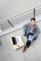 ung asiatisk affärsman som använder surfplatta, mobiltelefon på kontoret foto