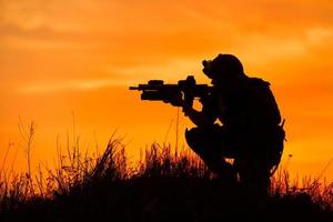 silhuett av militär soldat eller officer med vapen vid solnedgången