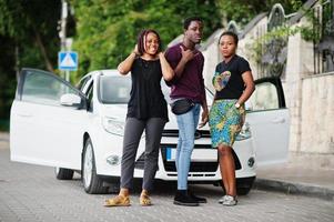 tre afroamerikanska vänner stannar nära bilen. foto