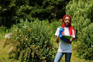 afrikansk rödhårig frivillig kvinna med urklipp i parken. Afrika volontärarbete, välgörenhet, människor och ekologi koncept. foto