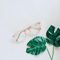 glasögon och gröna palmblad på grå bakgrund, minimal stil med vårkoncept foto