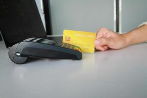 kvinna som använder kreditkortssvepmaskin för att sälja produkter i butiken till kunder. begreppet utgifter via kreditkort. foto