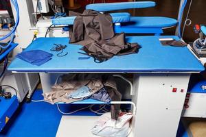 arbetsplatsen för en professionell klädskärare med ett ångstrykjärn och olika tyger. foto