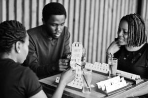 grupp på tre afroamerikanska vänner spelar bordsspel. foto