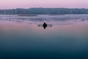 siluett av mannen i en båt tidigt på morgonen. rosa gryning foto