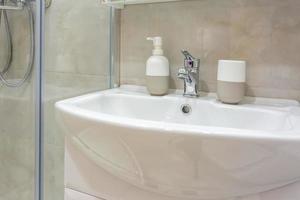 tvål och schampo dispensrar nära keramisk vattenkran handfat med kran i dyra loft badrum foto