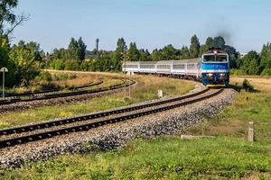 passagerartåg åker bland fält på en solig dag foto