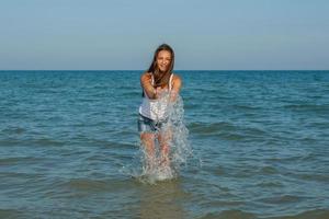 ung flicka plaska vattnet i havet foto