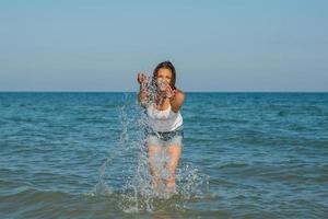 ung flicka plaska vattnet i havet foto