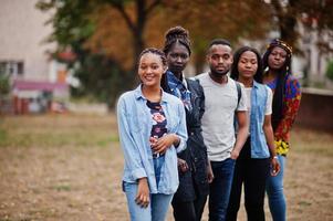 rad av grupp fem afrikanska högskolestudenter tillbringar tid tillsammans på campus på universitetsgården. svarta afro vänner studerar. utbildningstema. foto