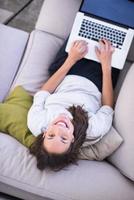 ung kvinna som använder laptop hemma ovanifrån foto