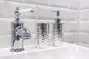tvål och schampo dispensrar nära keramisk vattenkran handfat med kran i dyra loft badrum foto