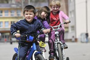 glad barngrupp som lär sig att köra cykel foto