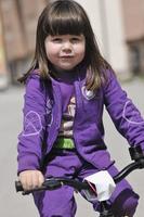 söt liten flicka kör cykel på solig dag foto