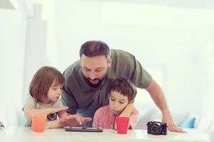 ensamstående pappa hemma med två barn som spelar spel på surfplatta foto