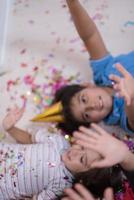 barn som blåser konfetti medan de ligger på golvet foto