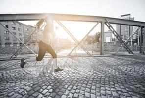 kvinna joggar över bron på solig morgon foto