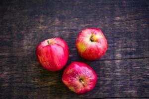 tre röda äpplen på träbord foto