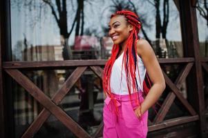 fashionabla afrikansk amerikansk flicka i rosa byxor och röda dreads poserade utomhus. foto