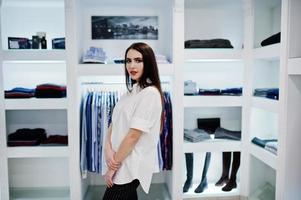 brunett vacker flicka i klädbutik boutique på casual kläder, vit blus och svarta byxor. foto