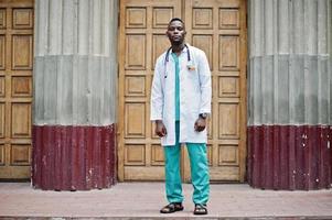 afrikansk amerikansk läkare man på labbrock med stetoskop utomhus mot klinikdörren. foto