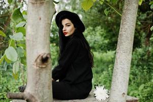 sensuell tjej helt i svarta, röda läppar och hatt. goth dramatisk kvinna. foto