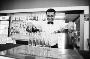 afroamerikansk bartender i baren gör cocktails på skott. beredning av alkoholhaltiga drycker. foto