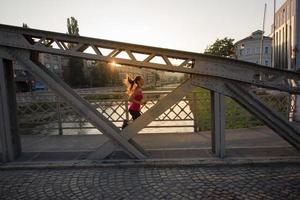 kvinna joggar över bron på solig morgon foto