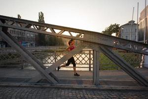 kvinna joggar över bron på solig morgon foto