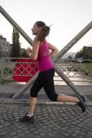 kvinna joggar över bron på solig morgon foto