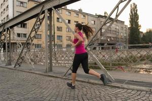 kvinna joggar över bron på solig morgon foto