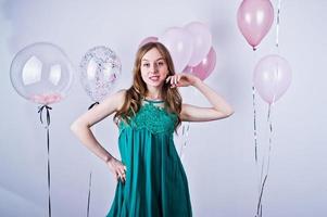glad tjej i grön turkos klänning med färgade ballonger isolerade på vitt. firande av födelsedagstema. foto
