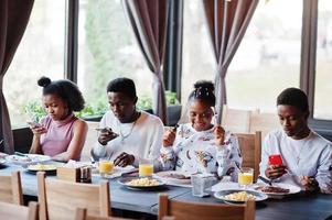 glada afrikanska vänner sitter, chattar på café och äter mat. grupp av svarta folk som träffas i restaurangen och äter middag. foto