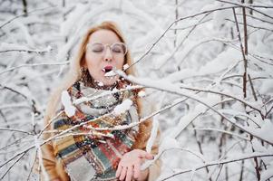 porträtt av blond flicka i glasögon, röd päls och halsduk på vinterdagen. foto