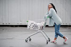 ingen mer plast. afrikansk kvinna med kundvagnsvagn och ekopåsar poserade utomhusmarknad. foto