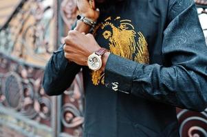 närbild händer av rik afrikansk man med klocka och manschettknappar. foto