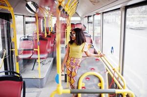 ung elegant afrikansk amerikansk kvinna i moderna solglasögon som åker på en buss. foto