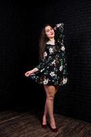 porträtt av en fantastisk ung kvinna i blommig klänning i den mörka studion. foto