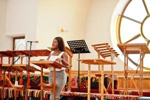 afrikansk amerikansk kvinna ber i kyrkan. troende mediterar i katedralen och andlig bönetid. afro tjej sjunger och förhärliga gud på refränger. foto