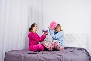 två vänner flickor i pyjamas ha kul på sängen på rummet. foto