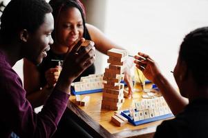 grupp på tre afroamerikanska vänner spelar bordsspel. foto