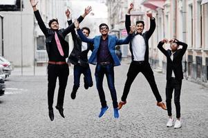 grupp på 5 indiska studenter i kostym poserade utomhus och hoppade. foto