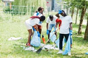 grupp glada afrikanska volontärer med soppåsar rengöringsområde i parken. Afrika volontärarbete, välgörenhet, människor och ekologi koncept. foto