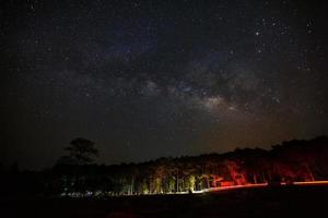 Vintergatan och siluett av träd med moln vid Phu hin rong kla nationalpark, Phitsanulok Thailand, långexponeringsfotografi, med korn foto